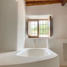 a white bath tub sitting under a window next to a wooden beam in a bathroom