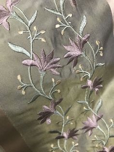 an embroidered fabric with flowers and leaves on the side, in shades of green and purple