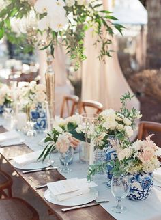 a table set with blue and white vases filled with flowers on top of it