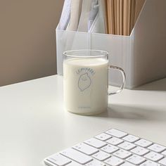 a cup of milk next to a computer keyboard