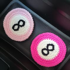 two pink and white crocheted buttons sitting on top of a car dash board