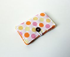 a polka dot wallet with a button on the front and an orange, yellow, pink, and white background