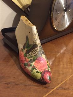 a wooden shoe sitting on top of a table next to a clock