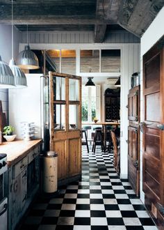 a kitchen with black and white checkered flooring next to an open door that leads into the dining room