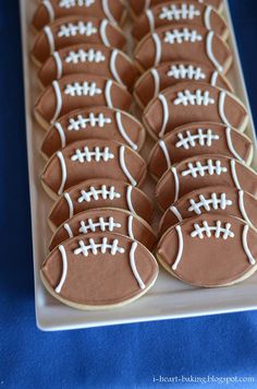 cookies decorated like footballs on a platter with blue tablecloth and white trim