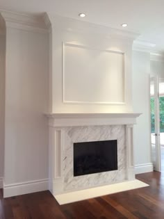 an empty living room with a fireplace and hard wood floors