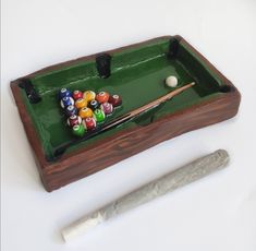 a pool table with billiards, cues and ball on it next to a knife