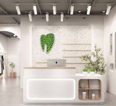 a white reception desk with a green leaf on the wall behind it and shelves below