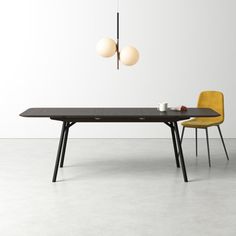 a dining table with two chairs and a light hanging from the ceiling in front of it