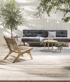 a living room filled with furniture next to a wooden table and tree in the corner