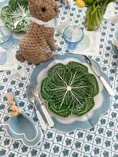 a table set with plates, utensils and stuffed animals on top of it