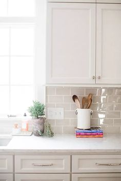 a kitchen with white cabinets and wooden utensils