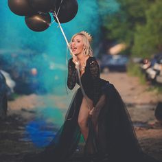 a woman in a black dress holding balloons