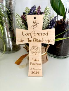 a wooden cross sitting on top of a table next to potted plants and vases