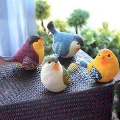 four small birds sitting on top of a wicker table