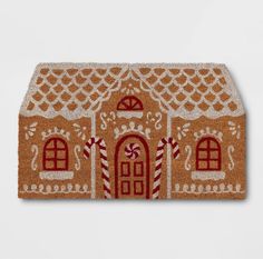 a gingerbread house door mat with candy canes on the front and side panels