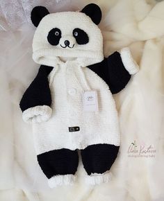 a stuffed panda bear wearing a white and black outfit with tags on it's chest