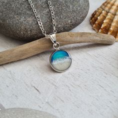 These pendants will conjure up happy memories spent by the sea. It is a perfect design for anyone with a love of the ocean. Ocean waves have been set in resin in this pendant frame, which is made from a 10mm stainless steel tray pendant that comes with an 18-inch silver chain necklace. - Each pendant is unique and impossible to replicate, making them special pieces - Perfect for gift giving to someone who loves the ocean - Comes in a reusable drawstring gift bag and wrapped in tissue paper with Handmade Ocean-inspired Sand Colored Jewelry, Handmade Sand-colored Ocean-inspired Jewelry, Ocean-inspired Jewelry With Round Pendant For Gift, Ocean-inspired Round Pendant Jewelry For Gift, Ocean-inspired Round Pendant Jewelry Gift, Ocean-inspired Jewelry As A Gift, Ocean-inspired Jewelry As Gift, Handmade Ocean Colored Pendant Jewelry, Handmade Ocean Color Pendant Jewelry