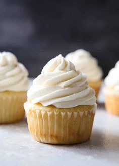 three cupcakes with white frosting sitting on a counter