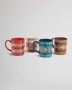 four mugs with designs on them are lined up against a white background and one has a red handle