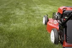 a red lawn mower sitting on top of a lush green field