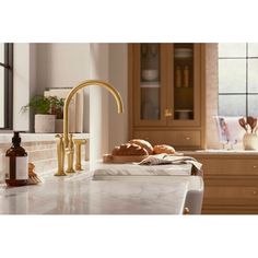 a kitchen with marble counter tops and gold faucet, along with bread on the counter