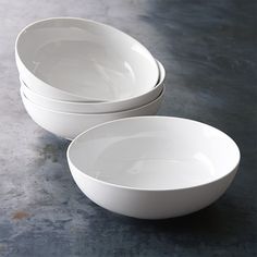 three white bowls sitting on top of a table next to each other in front of a gray background