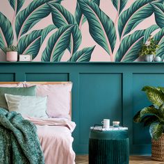 a bedroom decorated in teal and pink with palm leaves on the wall behind it