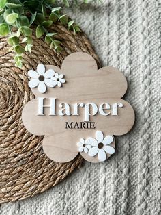 a wooden sign that says harper marie with white flowers on it next to a plant