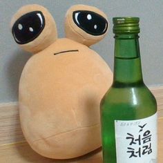 there is a stuffed animal next to a bottle on the table with it's eyes open