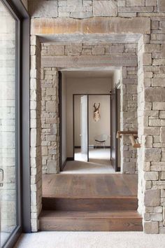 an open door leading to a room with stone walls and wood floors, along with a white rug on the floor