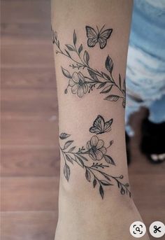 a woman's arm with flowers and butterflies tattooed on the back of her leg