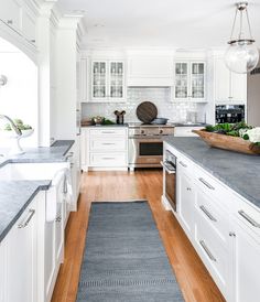 a kitchen with white cabinets and gray counter tops is seen in this image from the doorway