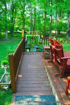 a wooden deck in the middle of a wooded area with benches and tables on it