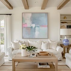 a living room filled with furniture and a painting hanging on the wall above it's coffee table