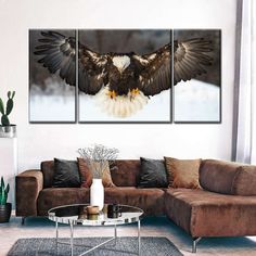 a living room with a couch, table and two paintings on the wall that have an eagle flying over it