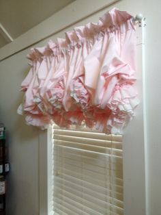 the pink ruffled valance is hanging on the window sill above the blinds