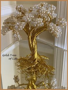 a gold wire tree with white flowers and pearls