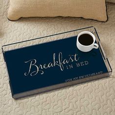 a bed with a tray that has a cup of coffee on it next to a pillow