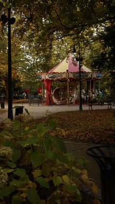 a carousel in the middle of a park surrounded by trees