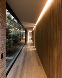 the hallway is lined with wooden planks and brick walls, along with large windows