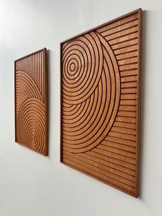 two wooden plaques mounted to the side of a wall next to each other on a white wall