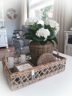 a wicker basket filled with flowers and candles on a table in front of a window