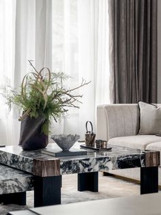 a living room with marble tables and couches in front of a large window filled with curtains