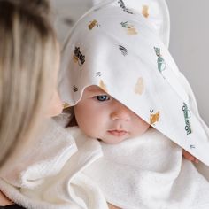 a woman is holding a baby wrapped in a blanket and looking at it's face