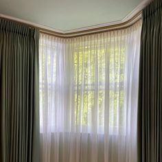 the curtains are hanging in front of the window, and there is a bed next to it