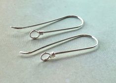 two pairs of silver earrings sitting on top of a table