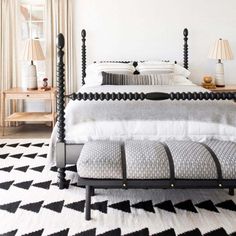 a black and white bedroom with four post bed, two nightstands and lamps on either side