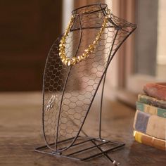 there is a metal stand with some gold necklaces on it next to several books