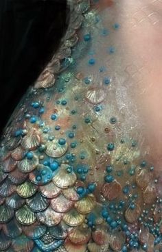 the back of a woman's body covered in blue and gold sequins